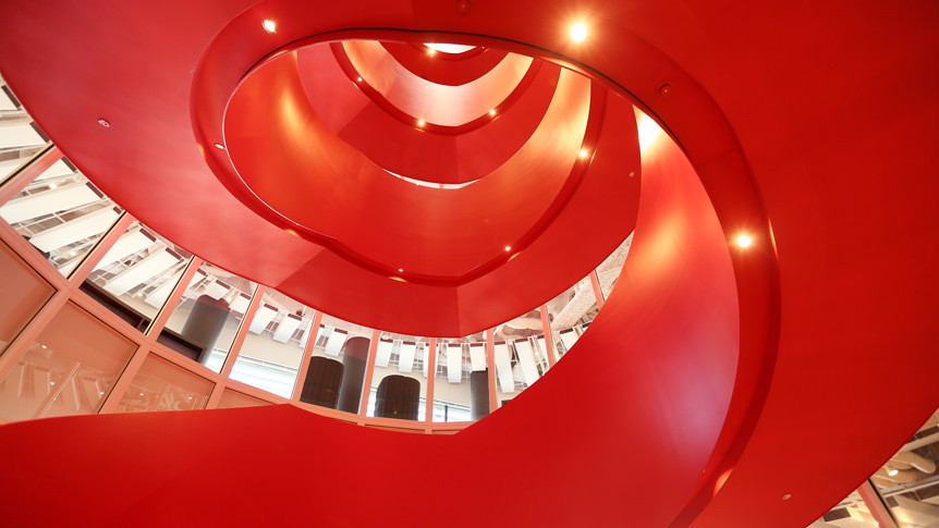 Red staircase in the center of the office, reminiscent of the interior of an engine