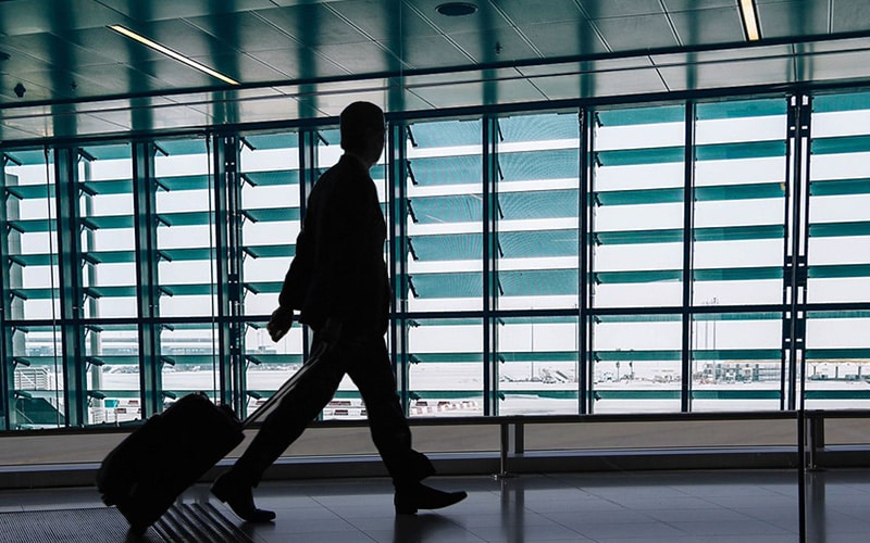 空港でスーツケースを引いて歩く人の写真
