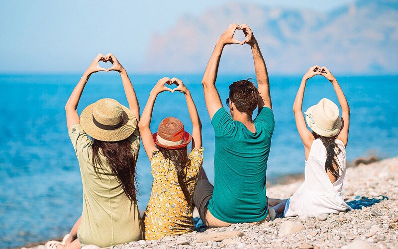 海沿いで手でハートを作って座っている人々の写真